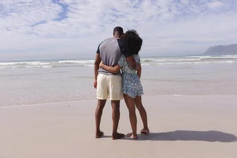 African american couple standing and embracing at the beach Stock Photos