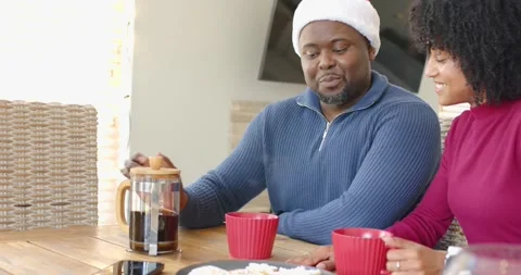 African American couple at table, man lifting press, pouring coffee into red mug Video stock 338060977