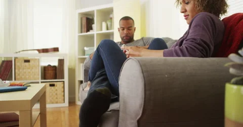 African American couple using devices on couch Video stock 44498173