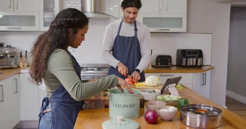 African American couple using tablet prepping veg on island using COMPOST for Stock Footage 339232422