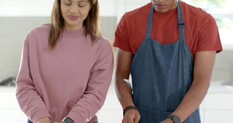 African American couple using tablet at counter, chopping carrots on board, Stock Footage 344964507