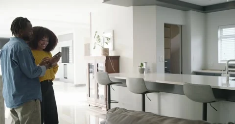 African American couple using tablet in living area, surveying kitchen island Stock Footage 348445169