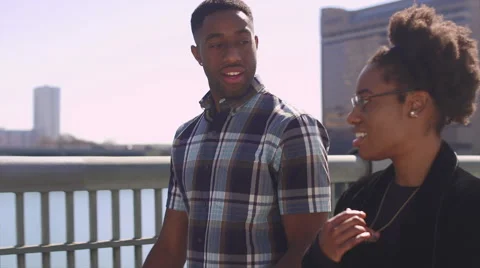 African American couple walking together along a city waterfront Stock Footage