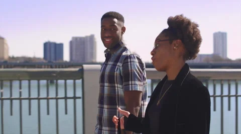 African American couple walking together along a city waterfront Stock Footage