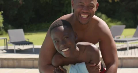 African American dad approaching, hugging teenage son holding towel, in trunks 스톡 동영상 336897925