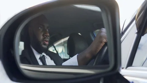 African American driving a car and looking in side-view mirror, being followed Stock Footage