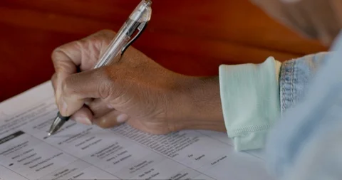 African American elderly woman voting and filling out a voter ballot Stock Footage