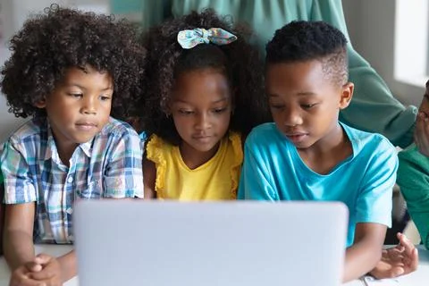African american elementary students using laptop while sitting at desk during Stockfoto's