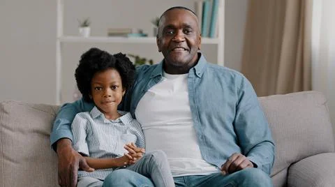 African american family sitting on sofa kid girl waving hello greeting adult Stock Photos