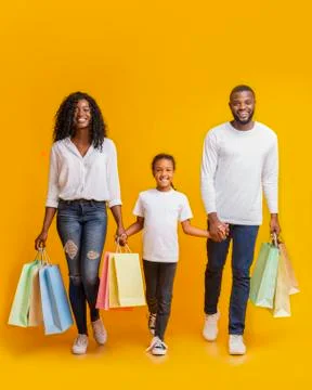 African American family of three walking with shopping bags in studio Stock Photos