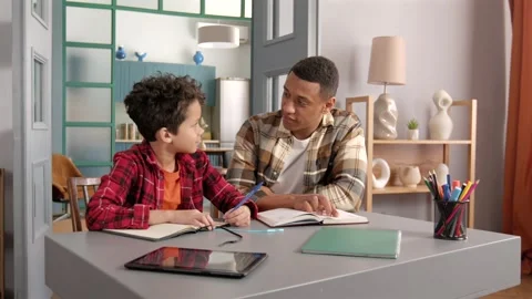 African American father with tutorial helping teenage son to do homework 動画素材 304407468