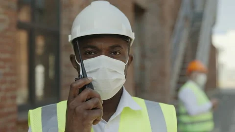 African american foreman in mask using walkie talkie outdoor Stock Footage 197487267