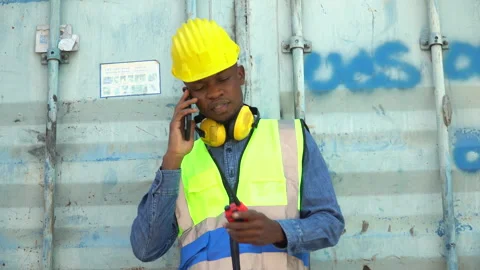 African american Foreman take a break talking on smartphone control loading.. Stock Footage 241724955