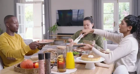 African American friends serving at dining table man extending plate, center Stock Footage 337731180