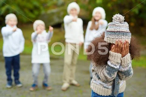 African-american girl expressing deep upset while several kids bullying her Stock Photos
