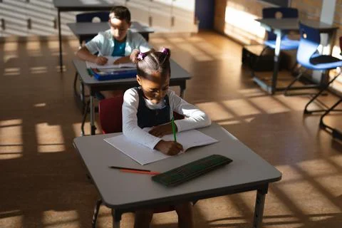 African american girl studying while siting on her desk in class at elementary Stock Photos