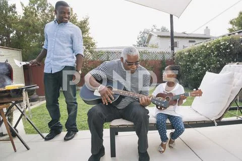 African American Grandfather Teaching Granddaughter To Play Guitar