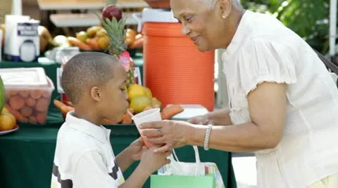 African American grandmother giving grandson orange juice Stock Footage