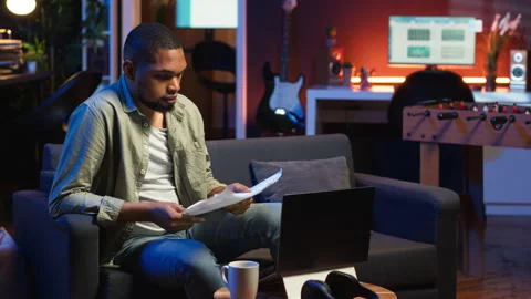 African american guy does research by reading articles and data driven papers Stock Footage 308262356