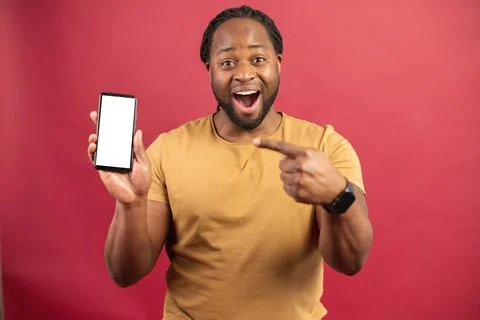 African-American guy points at empty phone screen isolated on red Stock Photos