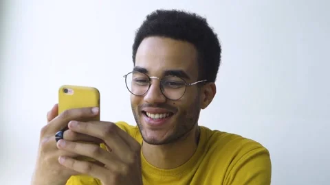 African-American guy smiles while looking at his smartphone Stock Footage 164057474