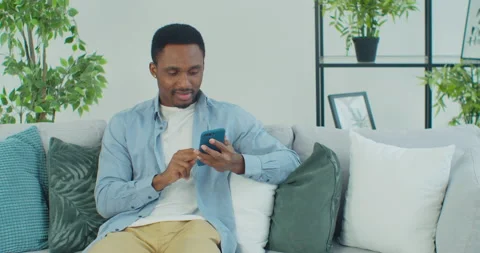 African-American guy using smartphone for messaging, scrolling news, reading Stock Footage 151600307