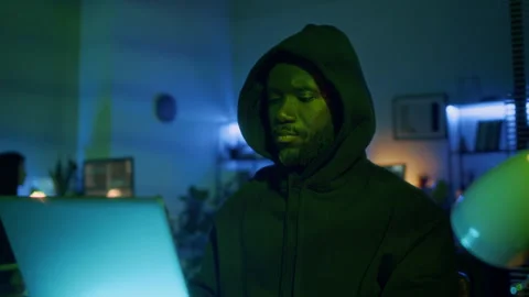 African American Hacker Dressed in Black Hoodie Stealing Data from Laptop Stock Footage 299262904