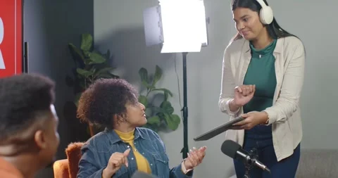African American hosts in studio handing tablet, seated host reviewing notes, 動画素材 344964155