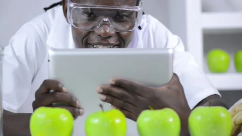 African American lab technician studying nutrition of food with a tablet compute Vídeos de archivo 199629204