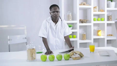 African American lab technician studying nutrition of food with a tablet compute Vídeos de archivo 199629260