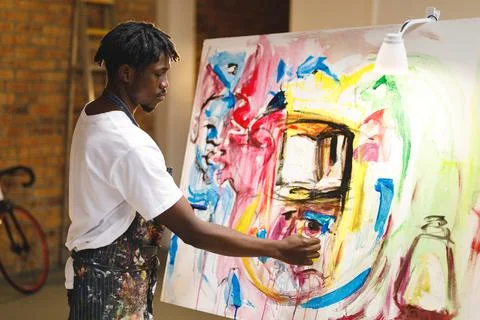 African american male painter at work painting on canvas in art studio Stock Photos