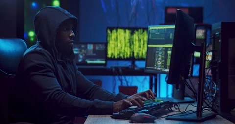 African American male software developer in a hood sitting at the two computers Stock Footage 124349328