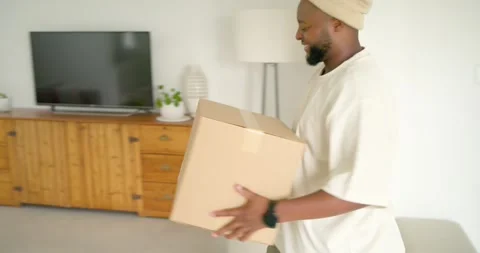 African American man accepting package at door carrying box home placing on Stock Footage 335987144