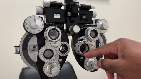 African American Man adjusting dials on phoropter used for eye examination or te Stock Footage 180488662