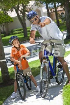 African american man & boy, father and son riding bikes Stock Photos