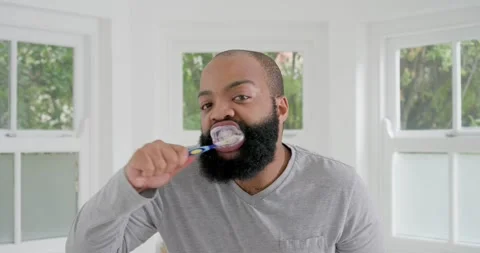 African American man bringing blue brush to mouth at home, brushing foamy teeth Stock Footage 336536498