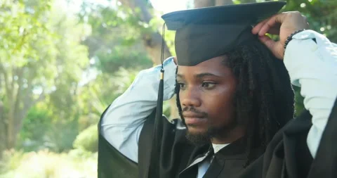 African American man checking fit adjusting cap fixing gown checking tassel in Stock Footage 340882342