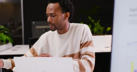 African American man checking laptop at desk leaning reaching tablet showing Stock Footage 342284449