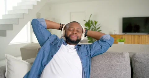 African American man checking phone scrolling reclining on sofa at home Stock Footage 336437879