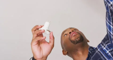 African American man checking plug and installing white recessed light into home 库存影片 341932903