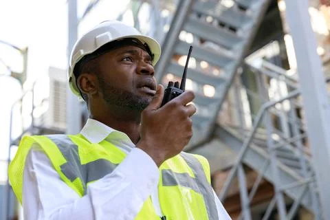 African american man controller in protective white hardhat using walkie talkie Stock Photos