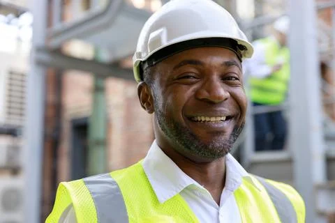 African american man controller in protective white hardhat standing, smiling Stock Photos