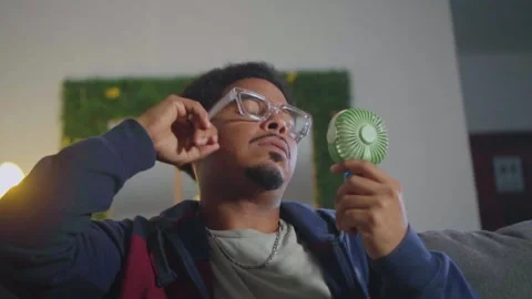 African american man cooling down with portable fan Stock Footage 340161937