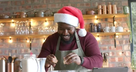 African American man cracking eggs into bowl in kitchen checking tablet recipe Stock Footage 339651141