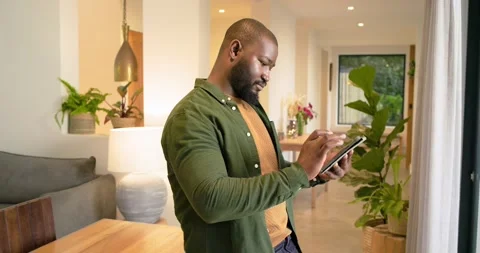 African American man at dining table annotating content with stylus on tablet, Stock Footage 319779681