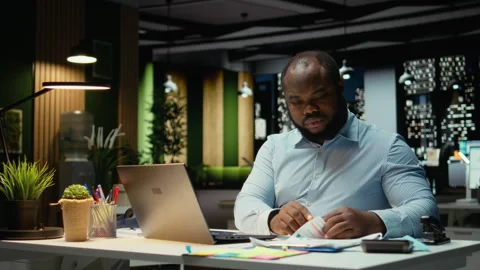 African american man does critical thinking and proofreading with papers Video stock 320088103