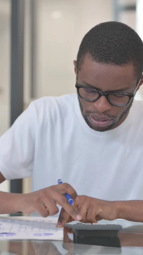 African American Man Doing Paperwork and Calculation, vertical video Stock Footage 324695504