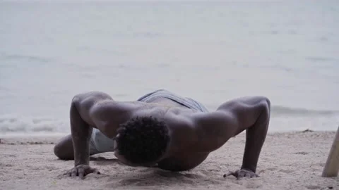 African American man doing pushups while exercising at the beach Vídeo Stock 142055371