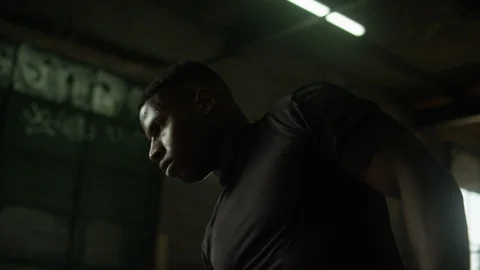 African American man doing side bend stretches in industrial-style gym Video stock 124452340