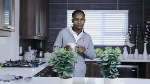 African American man drinking warm drink in modern kitchen 스톡 동영상 199630062